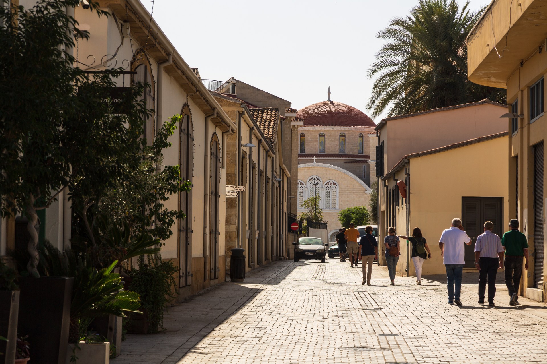 Emberek sétálnak Nicosia óvárosának egyik szűk utcáján egy kupolás székesegyház felé